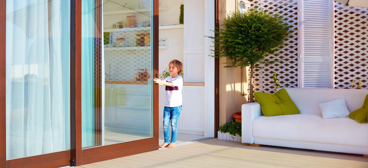young child opening up a glass bi-fold door